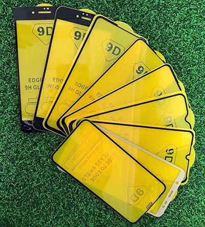 Yellow 90-series phone screen protectors arranged on a green surface